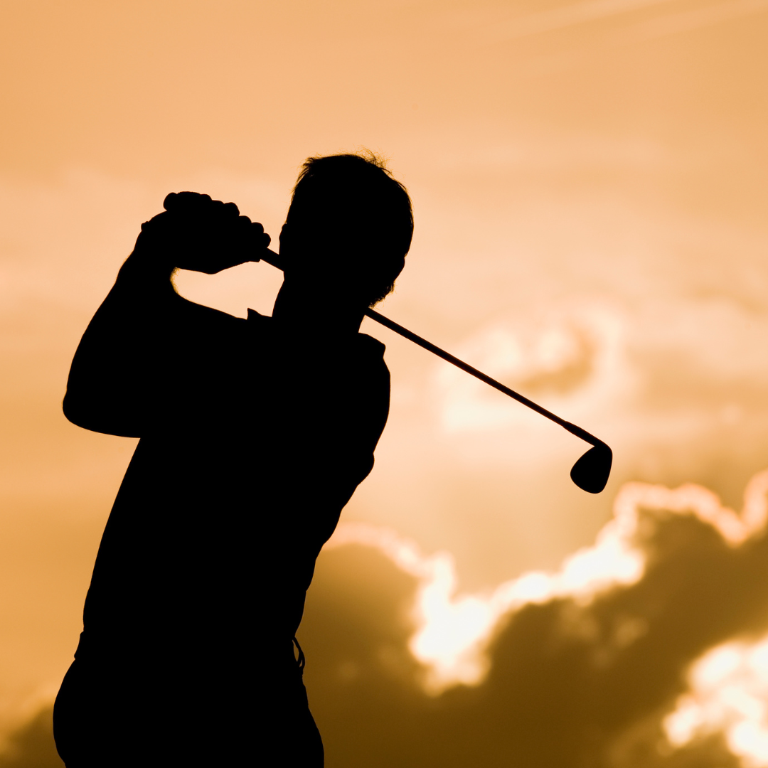 A golfer swinging during a sunset